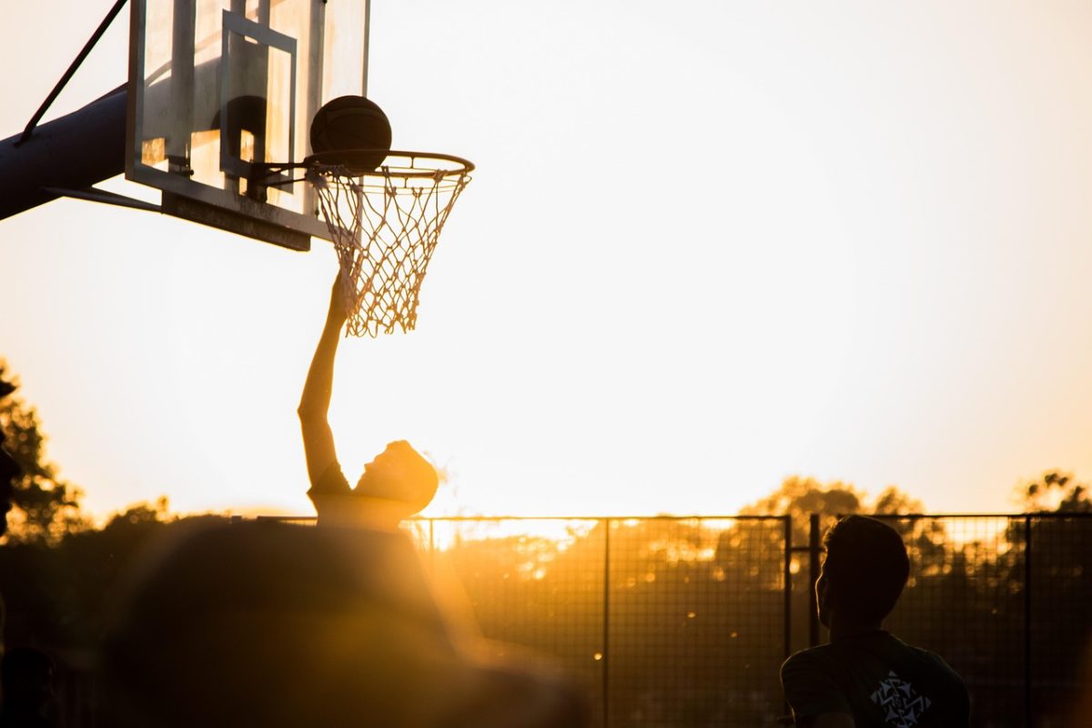 Jeune qui joue au basket au couché de soleil et qui vont marqué au panier