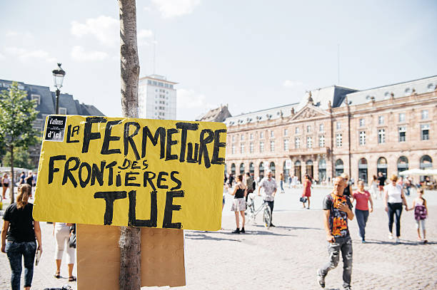 Pancarte militante affichée sur un arbre avec le message La fermeture des frontières tue lors d'une manifestation en ville
