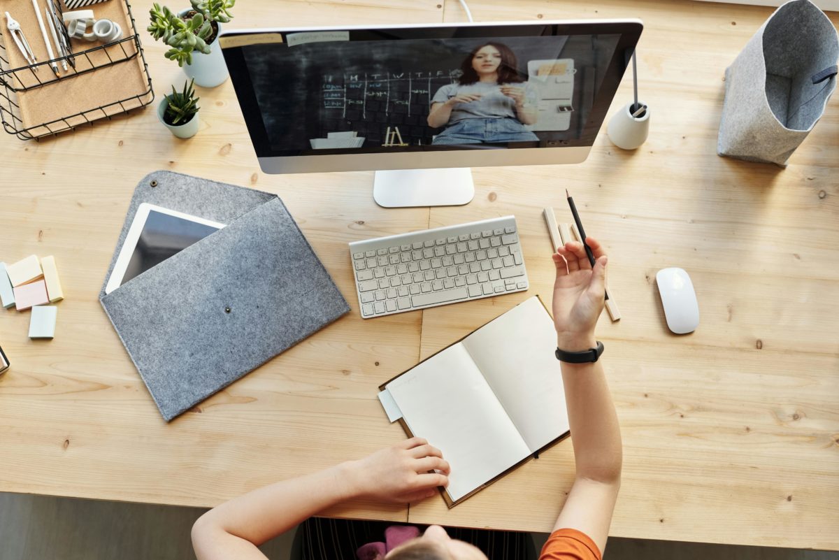 Étudiant en blocus en FaceTime avec une amie et prenant des notes sur un bureau en bois, concentration et entraide pendant les révisions.