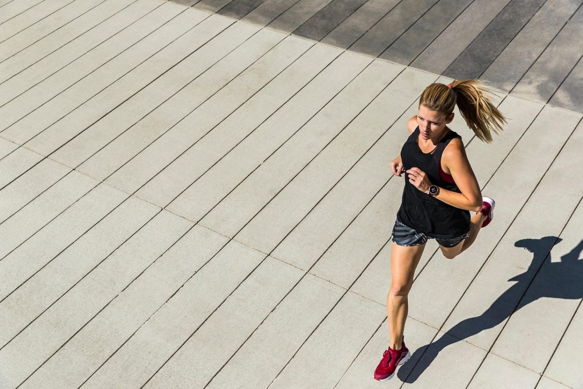 Femme en train de faire du sport en courant à l’extérieur sur une surface en bois