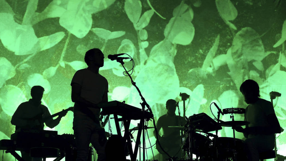 Silhouette d’un groupe de musique sur fond vert symbolisant l’engagement écologique dans l’industrie musicale.